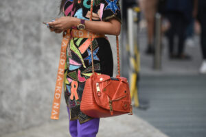 Woman in purple and yellow floral dress carrying brown leather s
