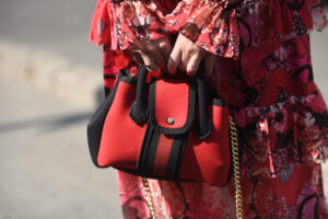 Person in red and white floral dress holding black and white lea